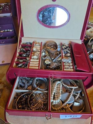 a pink suitcase filled with lots of jewelry on a table