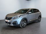 La voiture argentée est garée dans une grande pièce au sol noir.