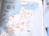 un livre ouvert, sur lequel figure une carte, posé sur une table
