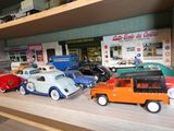 Plusieurs petites voitures sont alignées sur une étagère devant un magasin.