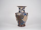 un vase bleu et or posé sur une surface blanche
