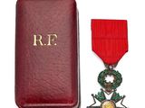 une image représentant un écrin rouge orné d'une médaille en or et d'un ruban rouge