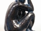 a black sculpture of a man sitting on a pedestal