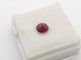 a close up of a red ruby stone sitting on a white surface