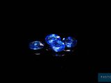 un gros plan sur trois saphirs bleus posés sur une surface noire