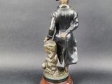 statue of a man with a dog on a wooden base