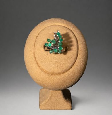 une bague sertie d'une pierre verte, posée sur un socle