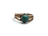 Gros plan sur une bague ornée d'une pierre verte