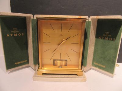 une horloge posée sur une table, dans un vitrin