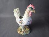 porcelain figurine of a rooster on a stand on a gray background