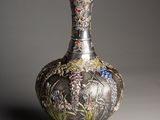 a silver vase with a floral design on it