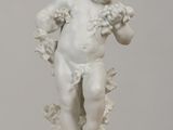 une statue blanche représentant un enfant tenant une fleur