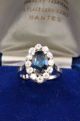 a close up of a ring with a blue stone surrounded by diamonds