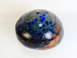 a blue and green glass ball on a white surface