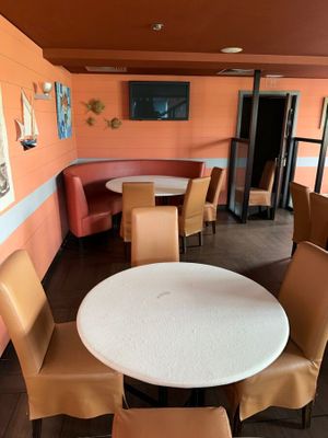 tables and chairs in a restaurant with orange walls and pictures on the wall