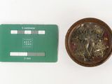 a small bowl of dried plants next to a green credit card