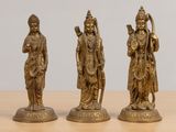 three brass figurines of hindu deities on a wooden table