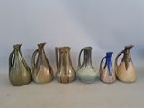 five different colored vases lined up in a row