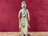 Une vieille statue représentant une femme avec une canne trône sur une table.