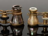 three antique brass binoculars sitting on a black surface