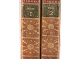two old books sitting on top of each other on a white surface
