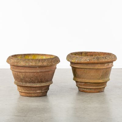 two large pots sitting on a concrete floor