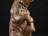 statue d'un ours brun assis sur ses pattes arrière, sur fond noir