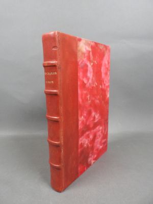 an old red book sitting on top of a gray surface