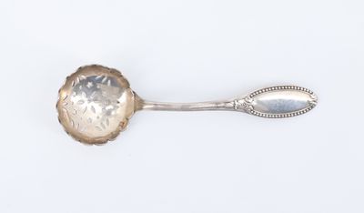 une cuillère ancienne en argent dont le manche repose sur une surface blanche
