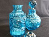 two blue glass vases sitting next to each other on a table