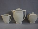 three white teapots and two cups on a table