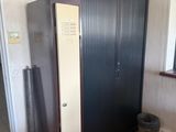 a black cabinet in the corner of a room next to a window