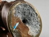 a hand holding a pipe with a blue stick sticking out of it
