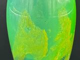 un vase vert et jaune posé sur une table noire