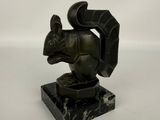 statue d'un écureuil posée sur un socle en marbre noir, sur fond blanc