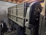 a military truck with a flat bed in a garage