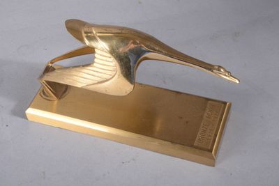 sculpture en laiton représentant un oiseau posé sur un socle, sur une surface blanche