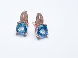 paire de boucles d'oreilles en topaze bleue et diamants sur fond blanc