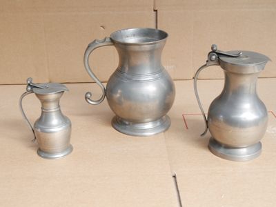 three silver vases sitting on the floor next to each other