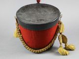 a red and black drum with tassels on top of it