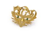 a close up of a gold brooch with green stones