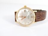 une montre en or avec un cadran blanc et un bracelet en cuir marron