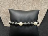 a black and white beaded bracelet on a black pillow
