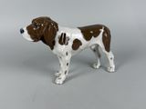 a figurine of a brown and white dog on a gray background