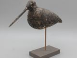 statue représentant un oiseau au long bec, posée sur un socle en bois