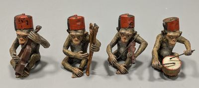 three figurines of monkeys with drums and hats on their heads
