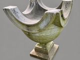 a stone bowl on a pedestal on a gray background