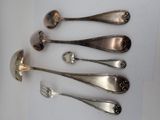 six spoons and a fork are arranged in a row on a table