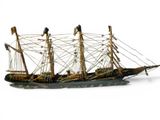 a small model of a sailing ship on a white surface