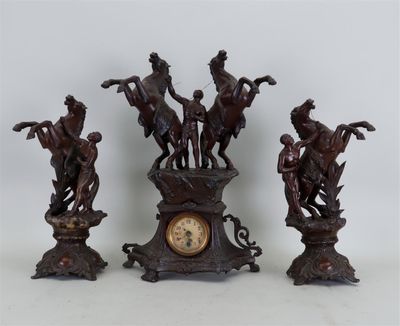 trois figurines de chevaux en bronze et une horloge posées sur une table